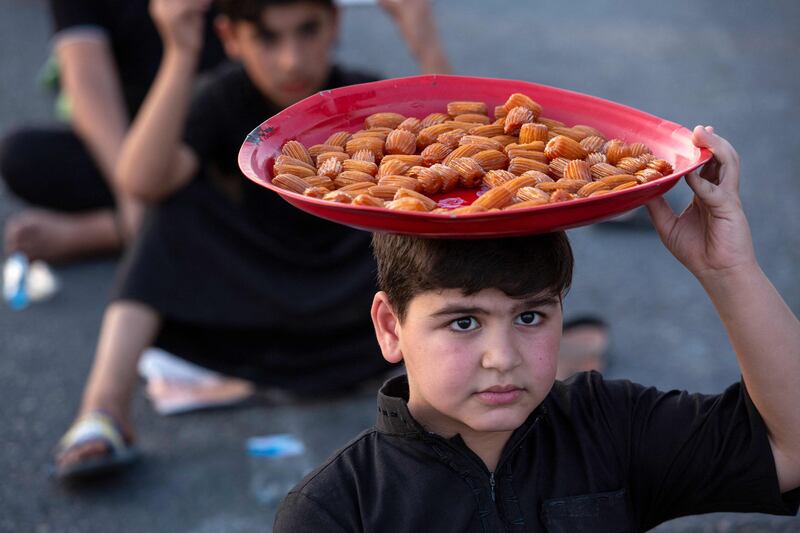 A boy distributes sweets to Iraqi Shiite Muslim pilgrims marching from the southern port city of Basra to the holy city of Karbala, ahead of the Arbaeen festival. AFP