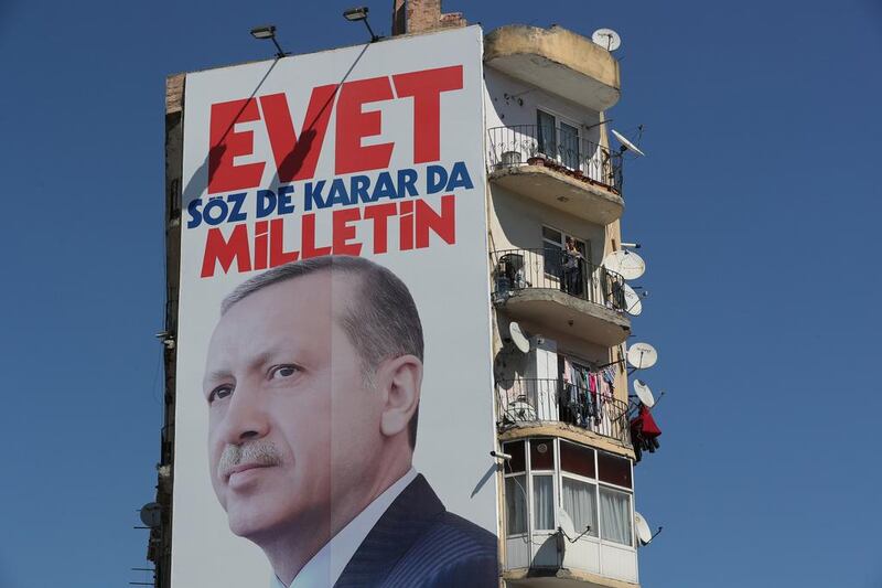 A woman stands on her balcony near a giant poster of Turkish president Recep Tayyip Erdogan reading, 'Vote Yes, only [the] public can speak and make decision', in Istanbul on March 29 2017. Tolga Bozoglu / EPA