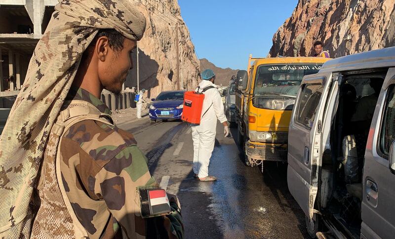 Members of Yemen's separatist Southern Transitional Council (STC) man a checkpoint while workers disinfect vehicles at the entrance of Mualla, a district of the southern province of Aden, amid the COVID-19 pandemic on May 10, 2020. (Photo by - / AFP)