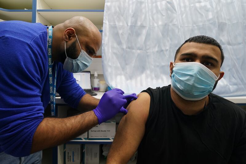 Nurse Salak Ali administers a vaccination booster injection to Miten Patel in north London on December 23, 2021. PA