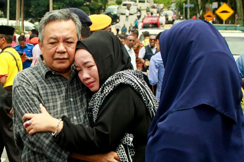 Nik Azlan Nik Abdul Kadir, father of one of the victims comforts his wife outside the Darul Quran Ittifaqiyah religious school in Kuala Lumpur. Sadiq Asyraf / AFP Photo