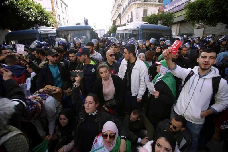 Demonstrators gesture near police officers standing guard during a protest against the country's ruling elite and calling to reject the upcoming presidential election in Algiers. REUTERS