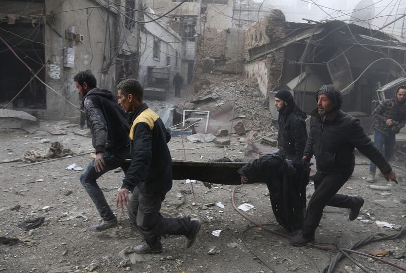 Syrian civil defence volunteers carry away an injured man after regime air strikes in Jisreen on February 8, 2018. Abdulmonam Eassa / AFP