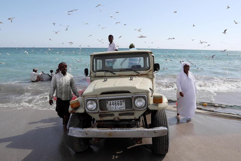 SHARJAH , UNITED ARAB EMIRATES , NOV 22   – 2017 :- Sultan Rashid , fisherman and owner ( right ) with the old Toyota Land Cruiser after fishing near the corniche area at Kalba in Sharjah. Sultan Rashid is from Kalba and doing fishing for the last 30 years. Fishermen are using old Toyota Land Cruisers for pulling the fishing net. The whole process of fishing with these old Land Cruisers is around 5 to 6 hours.  (Pawan Singh / The National) For Weekend