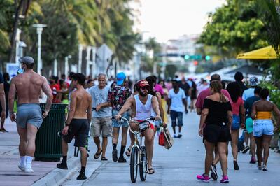 (FILES) In this file photo taken on June 26, 2020 A man rides a bicycle as people walk on Ocean Drive in Miami Beach, Florida on June 26, 2020.  Florida on June 27, 2020 hit a new daily coronavirus case record of nearly 10,000 -- a dramatic setback that several other states are also experiencing as economic reopenings clash with public health realities. / AFP / CHANDAN KHANNA
