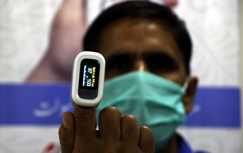 An aid worker of Alkhidmat Foundation is showing pulse oximeter as the organization gives free of cost oxygen cylinders and such meters to COVID-19 patients at their homes. Imran Mukhtar/ The National