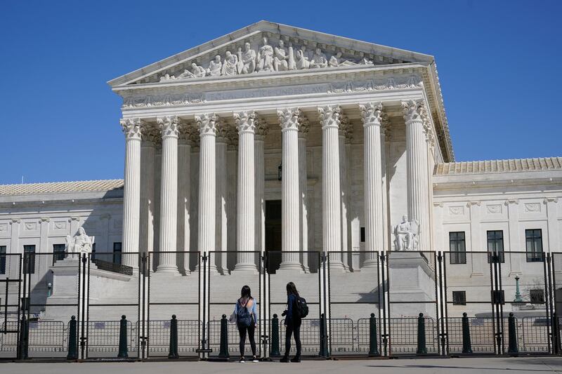 People view the Supreme Court building from behind security fencing on Capitol Hill in Washington, Sunday, March 21, 2021, after portions of an outer perimeter of fencing were removed overnight to allow public access. (AP Photo/Patrick Semansky)