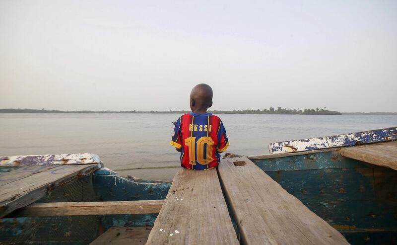 A boy sits on a fishing boat wearing a football shirt with the name and number 10 of Lionel Messi of FC Barcelona, in FC Barcelona compound in Fanti town, Robertsport, Grand Cape Mount County, Liberia. EPA