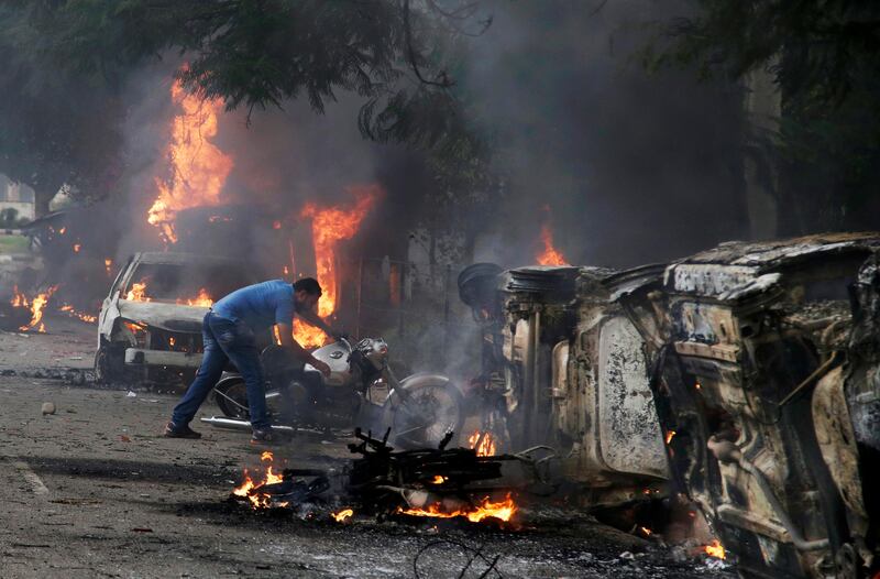A man tries to retrieve a motorcycle during the riots. Altaf Qadri / AP Photo