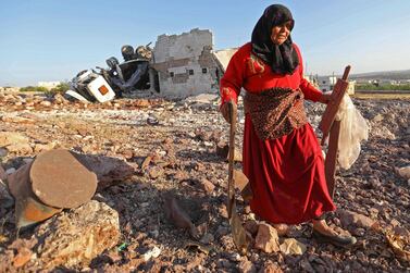A woman salvages items from a building reportedly destroyed during air strikes by Russia, in the town of Kafranbel in the rebel-held part of Idlib province. AFP / Omar Haj Kadour