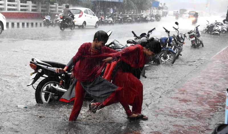 epa07727759 Indian women cross a water logged street during heavy monsoon rain in Bhopal, India, 19 July 2019. Following a long period of hot dry weather, the showers are mostly welcomed by locals as they bring a temporary relief from the recent heat.  EPA/SANJEEV GUPTA