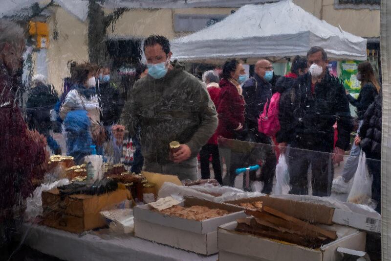 People seen through plastic sheets walk past street stalls selling food on a street in downtown Barcelona. AP Photo