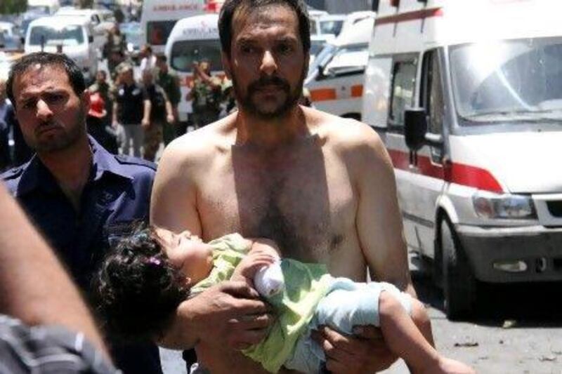 A Syrian man carries a wounded girl after an explosion that targeted a military bus in Damascus on Friday.