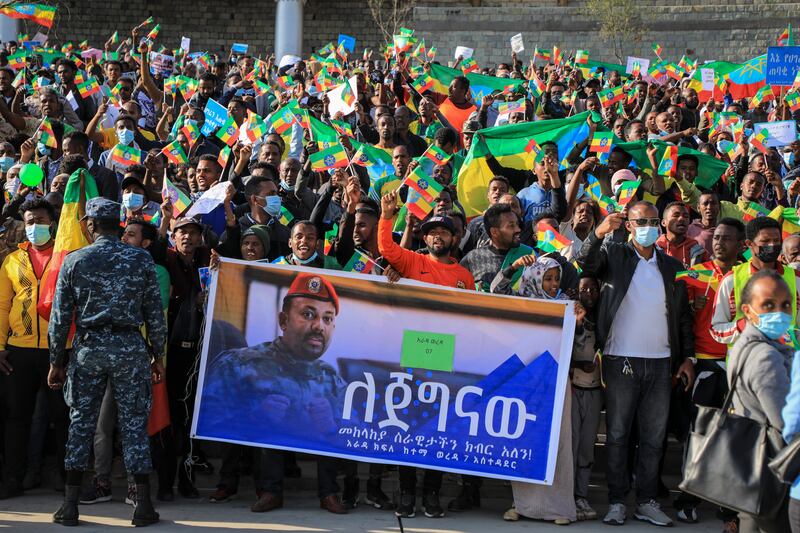 People gather behind a placard showing Prime Minister Abiy Ahmed at a rally organised by local authorities to show support for the Ethiopian National Defence Force in Addis Ababa. AP