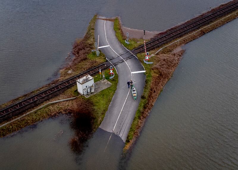 Two men pull their boat over a railroad crossing near Frankfurt, Germany. Fields were flooded by heavy rainfall. AP