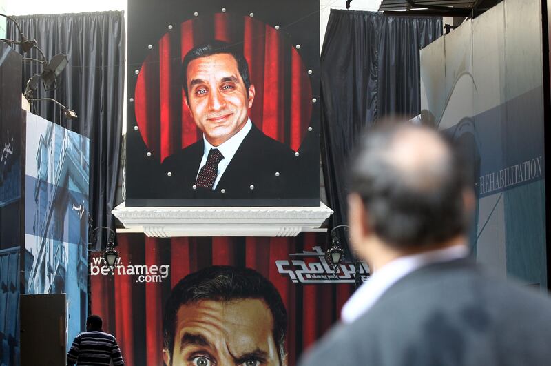 epa03522300 An Egyptian man stands in front of banners depicting Egyptian satirical TV show host Bassem Youssef in front of a theater in Cairo, Egypt, 02 January 2013. Egyptian prosecutors on 01 January began investigating Youssef for allegedly defaming President Mohamed Morsi on his program. Youssef has been satirizing speeches by Islamists in his recent episodes, broadcast on a private Egyptian Satellite channel. Youssef is known as "Egypt's Jon Stewart" - a reference to the US political satirist who hosts Comedy Central's Daily Show.  EPA/KHALED ELFIQI *** Local Caption ***  03522300.jpg