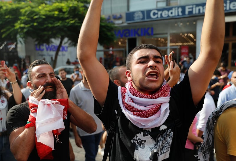 Anti-government protesters shout slogans near the scene where a Lebanese man killed himself on Beirut's commercial Hamra Street, apparently because of the deteriorating economic and financial crisis in the country, in Beirut, Lebanon, Friday, July 3, 2020. The man left a note that reads in Arabic: "I am not heretic but hunger is heresy," words taken from a Lebanese song. Security officials said they were investigating the incident and motives for his suicide. (AP Photo/Hussein Malla)