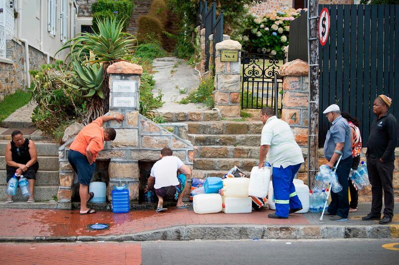 (FILES) This file photo taken on January 19, 2018 shows people collecting drinking water from pipes fed by an underground spring, in St James, about 25km from the city centre in Cape Town. 
Resident's of Cape Town's Nazareth House, a care home for dozens of vulnerable, disabled and orphaned children, are among the city's most vulnerable people. They now face the prospect that the water supply they depend on could be shut off within months as the three-year-long drought -- the worst in a century -- causes dam levels to dip below usable levels.
 / AFP PHOTO / RODGER BOSCH