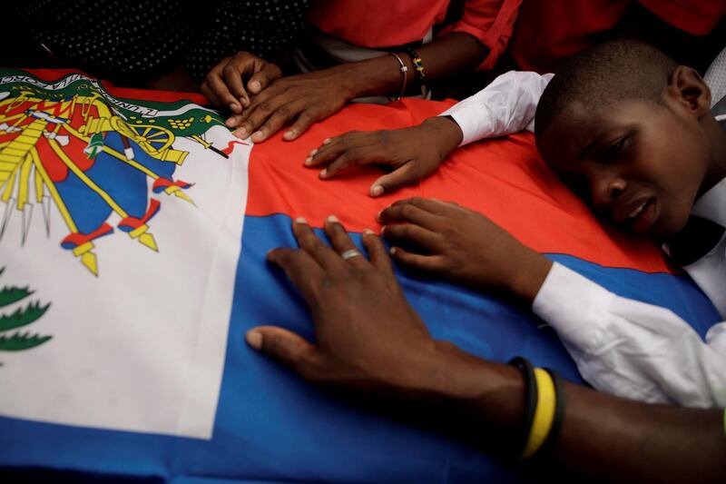 A boy cries on a Haitian flag placed on a coffin during a funeral of two men in Port-au-Prince, Haiti.  Reuters