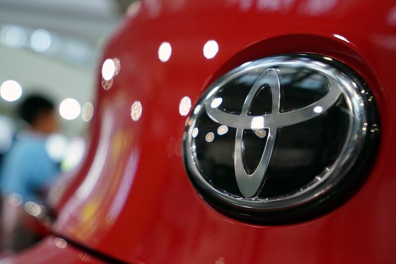 FILE - In this Aug. 2, 2019, file, photo, people walk by the logo of Toyota at a show room in Tokyo. Toyota will pay $180 million to settle U.S. government allegations that it failed to report pollution control system defects in its vehicles for a decade. The company, on Thursday, Jan. 14, 2021,  also agreed in court to investigate future emissions-related defects quickly and report them to the U.S. Environmental Protection Agency in a timely manner.  (AP Photo/Eugene Hoshiko, File)