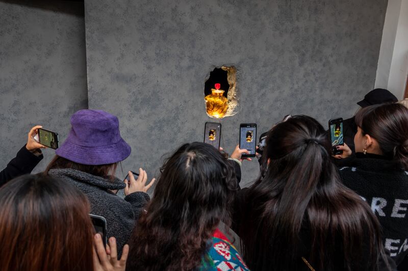 Customers take photos as a barista wearing a furry bear paw serves customers through a hole in the wall at Hinichijou coffee shop on December 3, 2020 in Shanghai, China. Getty Images