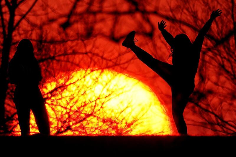 Girls are silhouetted against the setting sun as they enjoy a spring-like day in Kansas City, Missouri. AP