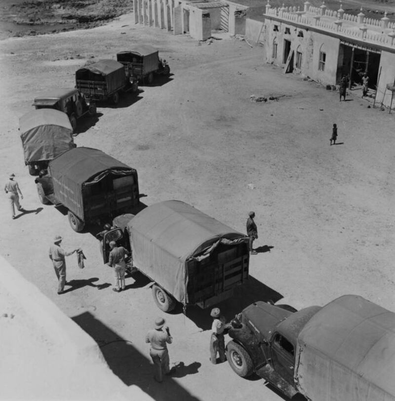 Wendell Phillips’ expedition caravan winds its way into the desert; one truck reads “American Foundation Arabian Expedition”. 