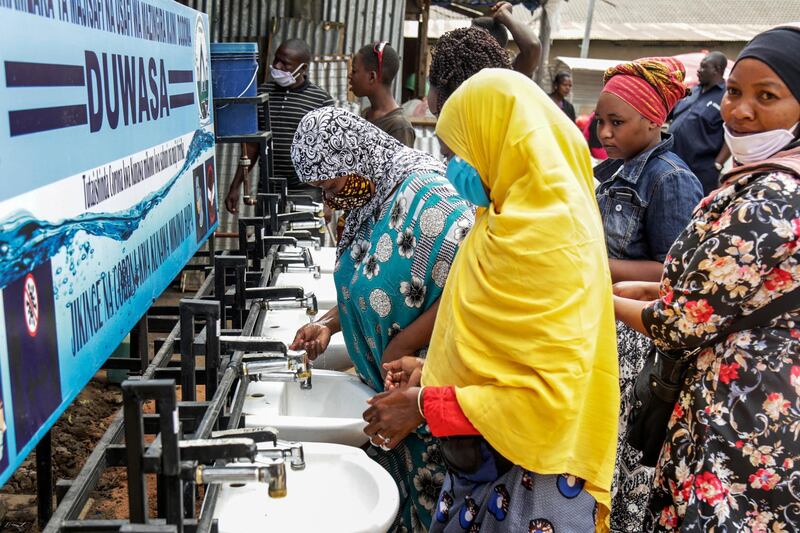 FILE - In this Monday, May 18, 2020 file photo, people use a hand-washing station installed for members of the public entering a market in Dodoma, Tanzania. Tanzania's president said Tuesday, June 16, 2020 that the country will reopen schools at the end of this month after claiming victory over COVID-19 but his comments come a day after his prime minister said 66 people are still infected and confusion has surrounded the East African nation after it stopped publicly updating its number of cases at the end of April. (AP Photo, File)