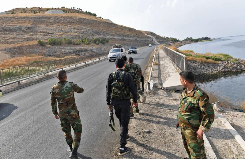 Syrian government soldiers walk along a road on the bank of the Euphrates river near the Qarah Qozak bridge in the north of Aleppo governorate near the border with Turkey in the countryside near the key border town of Kobane.  AFP