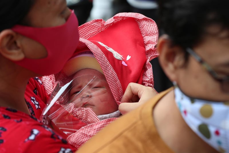 A mother carries her baby with face shield at a hospital in Jakarta, Indonesia. The world's Muslims have begun Ramadan with dawn-to-dusk fasting amid restrictions imposed to slow the pandemic that left many confined to their homes and public venues like parks, malls and even mosques are shuttered. AP