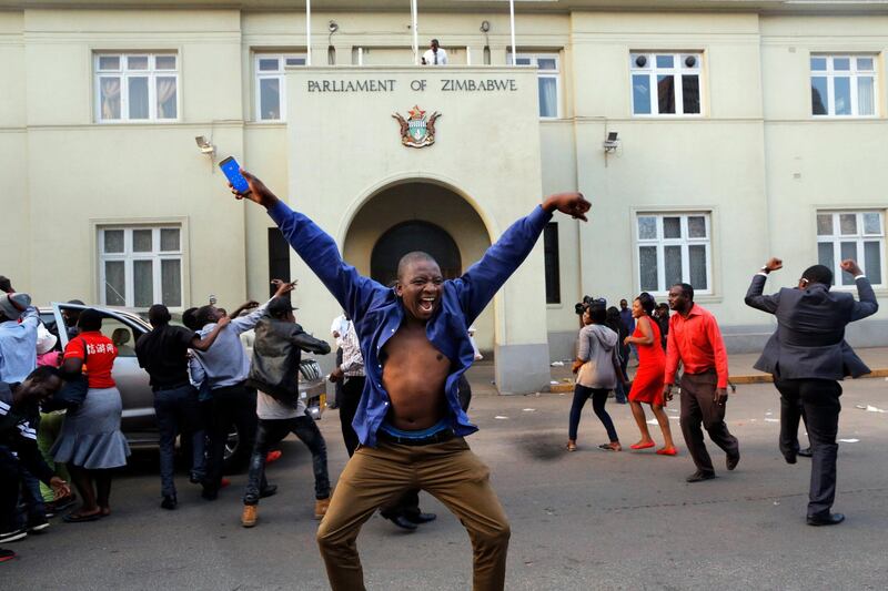 People celebrate outside parliament after hearing the news that president Robert Mugabe resigned in Harare. Kim Ludbrook / EPA