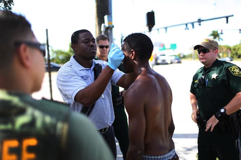 A paramedic takes the temperature of man suspected of being under the influence of flakka at Pompano Beach, Florida. Police officers surround the suspect in case he becomes violent. Joe Raedle / Getty Images