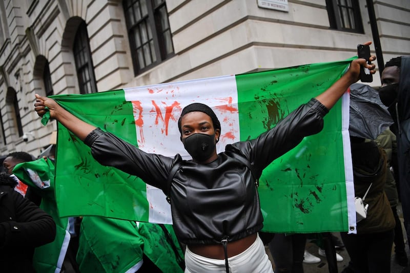 A protester holds a flag stained with fake blood during a demonstration outside the Nigerian High Commission in London.  AFP