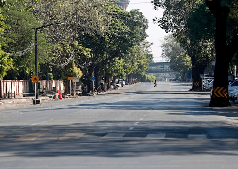 A woman crosses an empty street in downtown Yangon. For the silent strike, members of the public stayed at home and businesses closed from 10am to 4pm. EPA