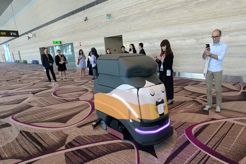 This photograph taken on July 25, 2017 shows journalists watching an automatic robot vacuum cleaning the floor during a media tour at the newly built Changi airport terminal 4 in Singapore.
New technology is rapidly being rolled out, transforming the exhausting experience of getting stuck in lengthy queues in ageing, overcrowded airport terminals into something far more pleasant. The Asia-Pacific has been leading the way but faces fierce competition from the Middle East as major hubs compete to attract the growing number of long-haul travellers who can choose through which regions to route their journeys. / AFP PHOTO / ROSLAN RAHMAN / TO GO WITH Aviation-technology-business,FOCUS by Sam Reeves