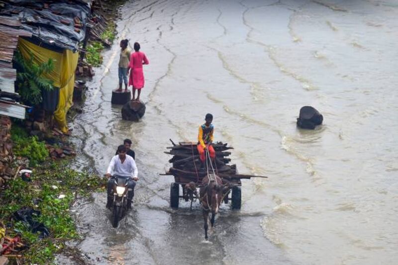 People wade along a flooded street near the banks of the Ganges in Allahabad. AFP