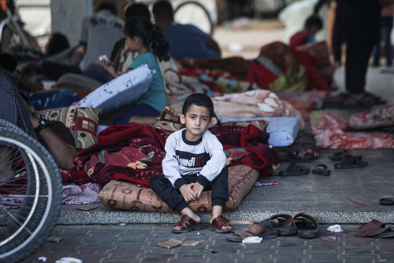 A five-year-old boy sits on a mattress in a shelter courtyard surrounded by several hundred other displaced people in Gaza. Photo: Unicef