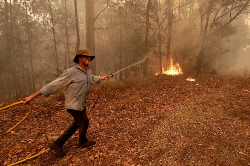 A man uses a water hose to battle a fire near Moruya, Australia. AP Photo