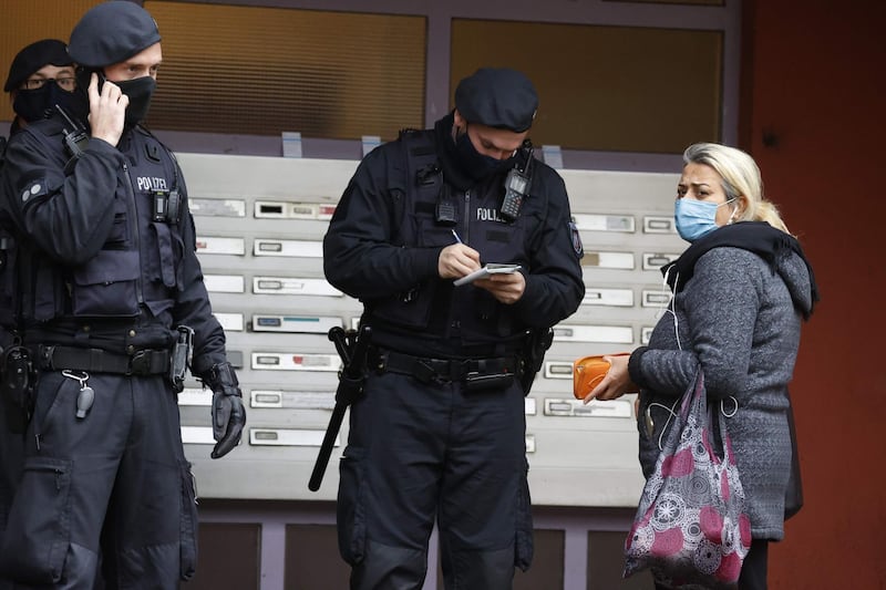 Policemen speak with a resident in front of a residential building in Berlin during the raids. AFP