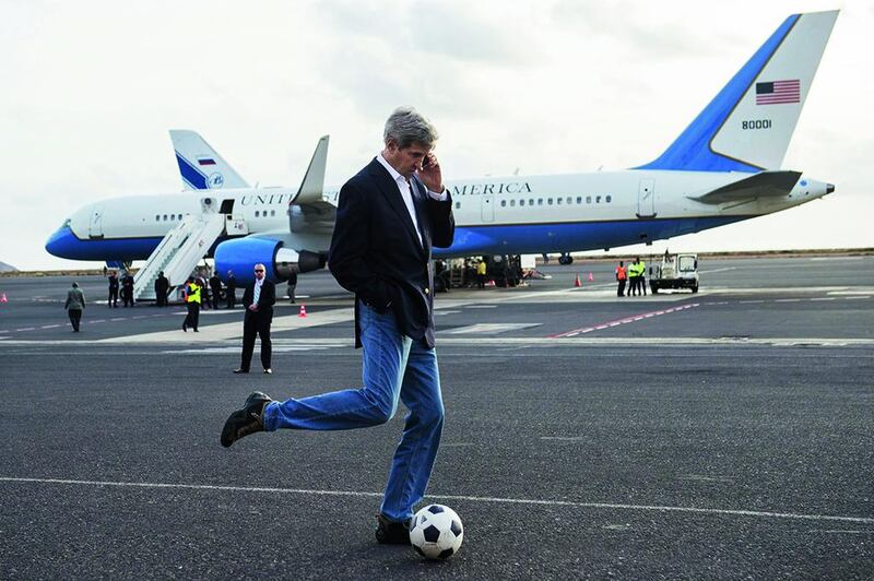 US Secretary of State John Kerry kicks around a soccer ball while talking on his mobile phone during an airplane refueling stop at Sal Island, Cape Verde, enroute to Washington, DC on May 5. Saul Loeb / AFP