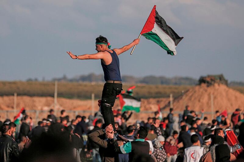 A Palestinian man carries the national flag during a demonstration near the fence along the border with Israel, east of Gaza City, on February 22, 2019. / AFP / MAHMUD HAMS
