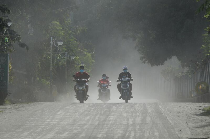 Motorcycle riders wear face masks as they travel along a road covered in ash in Tanuan, Batangas, Philippines.  EPA