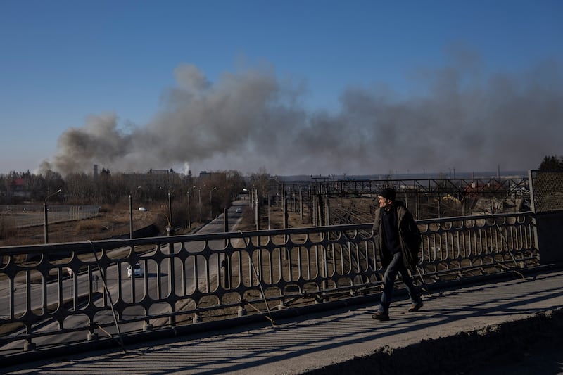 A pedestrian looks at a cloud of smoke rising after an explosion in Lviv. AP