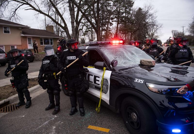 Law enforcement officers surround a smashed police vehicle in Brooklyn Centre, Minnesota, after a crowd gathered to protest against the death of Daunte Wright during a traffic stop earlier in the day. AFP