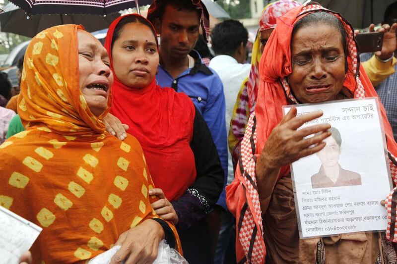 Family members of garments workers killed in the Rana Plaza factory collapse cry while holding photos of their beloved ones in front of the site of the Rana Plaza site during a memorial ceremony to mark the fourth anniversary of the disaster in Dhaka on April 24, 2017. Abir Abdullah / EPA
