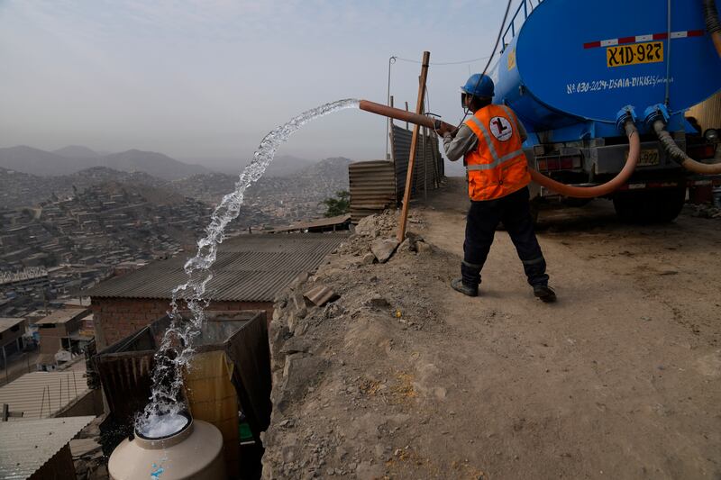 A water lorry worker fills tanks at houses in the Pamplona Alta area in Lima, Peru. Residents buy water for drinking, cooking and cleaning from private suppliers. AP 