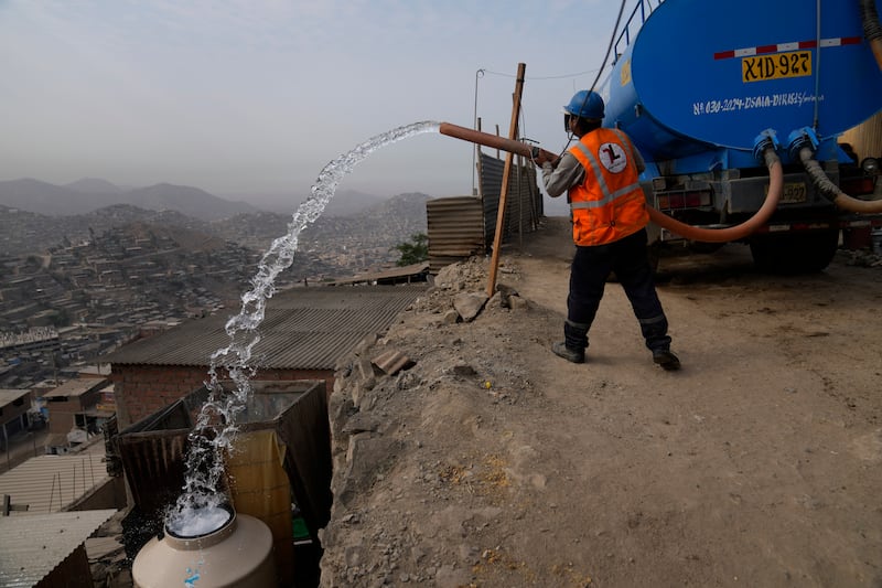 A water lorry worker fills tanks at houses in the Pamplona Alta area in Lima, Peru. Residents buy water for drinking, cooking and cleaning from private suppliers. AP 