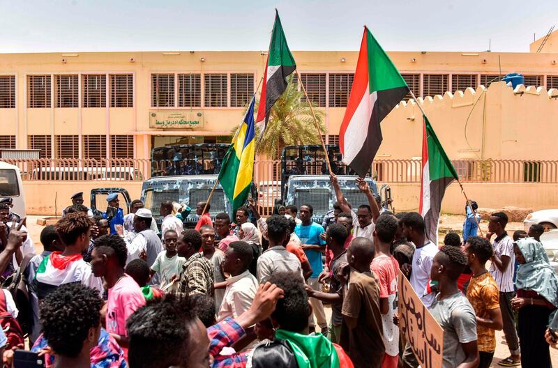 Demonstrators march with banners and the old (L) and current (R) flags of Sudan outside a courthouse complex in the capital's twin city of Omdurman on August 21, 2019 during the trial of 40 members of Sudan's now-dissolved National Intelligence and Security Service facing charges over the death in custody of Ahmed al-Kheir, a teacher from the eastern town of Khashma el-Girba, in the early days of the wave of nationwide protests that eventually brought longtime ruler Omar al-Bashir.  / AFP / Ahmed Mustafa                       
