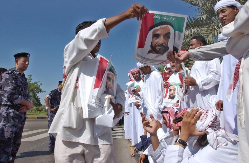 Mourners wave images of Sheikh Zayed as they wait for the funeral procession to pass by on the way to Sheikh Zayed Grand Mosque in November 2004. AP