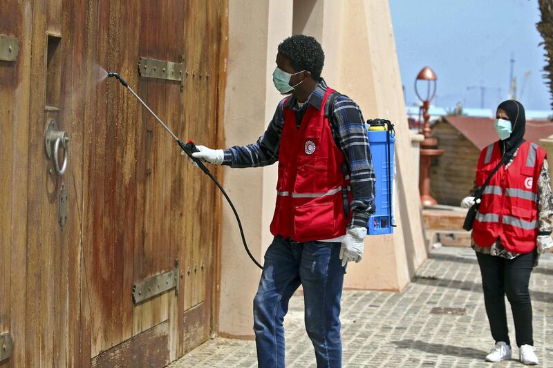 Members of the Libyan Red Crescent disinfect a street in the centre of the capital Tripoli on April 1, 2020, as a measure to stem the spread of the novel coronavirus that causes the COVID-19 disease, on April 1, 2020. (Photo by Mahmud TURKIA / AFP)